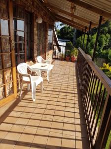 een patio met 2 stoelen en een tafel op een veranda bij Fig Tree Manor Self Catering in Blythedale