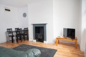 uma sala de estar com um sofá, uma televisão e uma mesa em Quire Court Apartment em Gloucester