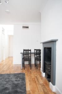 sala de estar con mesa, sillas y chimenea en Quire Court Apartment, en Gloucester