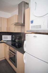 a kitchen with white appliances and wooden cabinets at Quire Court Apartment in Gloucester