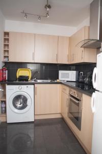 a kitchen with a washing machine and a microwave at Quire Court Apartment in Gloucester