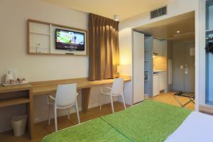 1 dormitorio con escritorio con 2 sillas y TV en Appart hôtel Q7 Lodge Lyon 7, en Lyon