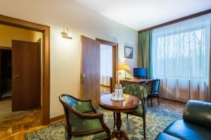 ein Hotelzimmer mit einem Tisch, Stühlen und einem Schreibtisch in der Unterkunft Arbat Hotel in Moskau
