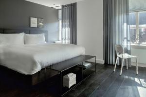 ein Schlafzimmer mit einem großen weißen Bett und einem Stuhl in der Unterkunft Kazerne Hotel - Member of Design Hotels in Eindhoven