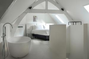 ein weißes Badezimmer mit Badewanne und Bett in der Unterkunft Kazerne Hotel - Member of Design Hotels in Eindhoven