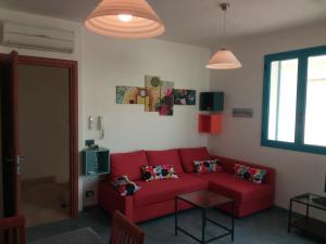 a living room with a red couch and a window at Casa Vacanze Kamarina in Punta Secca