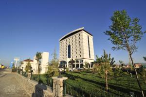 Grand Cenas Hotel في أغري: مبنى ابيض كبير امامه شجرة