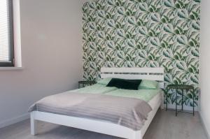 - une chambre avec un lit et du papier peint vert et blanc dans l'établissement Zielone Apartamenty, à Świeradów-Zdrój