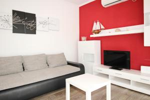 a living room with a black couch and a red wall at Apartment Mihaela in Baška