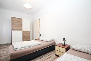 two beds in a room with white walls and wooden floors at Apartment Mihaela in Baška
