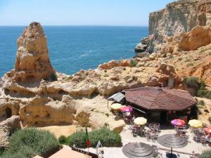 a group of tables and chairs with umbrellas and the ocean at Casa Marc in Carvoeiro