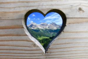 a heart shaped window with a view of a mountain at Gästehaus Mathies in Mittelberg