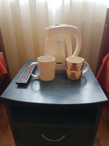 zwei Kaffeetassen und ein Mixer auf dem Tisch in der Unterkunft Hotel Erfolg in Daugavpils