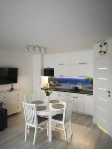 a white kitchen with a table and chairs in a room at Apartament na Wzgórzu in Mechelinki
