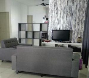 a living room with a couch and a television at Jauzara Homestay Berkolam Renang in Port Dickson
