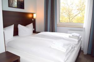 Un dormitorio con una cama blanca con toallas. en Trip Inn Budget Hotel Messe, en Frankfurt