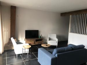 a living room with a couch and chairs and a tv at Vakantie Appartementen De Bonte Kraai in Raamsdonk