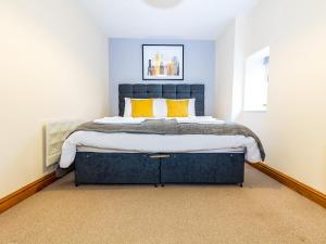 a bedroom with a large blue bed with yellow pillows at Guest Homes - New Street in Worcester