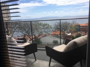 einen Balkon mit Stühlen und Blick auf das Wasser in der Unterkunft Tamariz Adventure - Sea View and Free Parking in Caniço