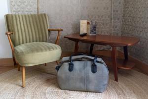 a bag sitting next to a chair and a table at Hotel Pastis in Maastricht