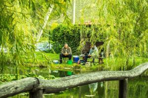 two men sitting in chairs by a pond at Эко Усадьба Эски Кермен in Bakhchysarai