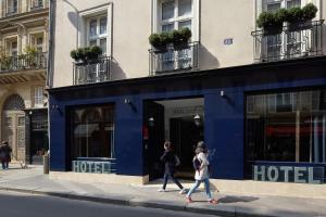duas pessoas a andar numa rua em frente a um hotel em Hôtel Saint Germain em Paris