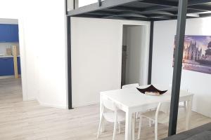 uma sala de jantar branca com uma mesa e cadeiras brancas em Solari7 em Milão