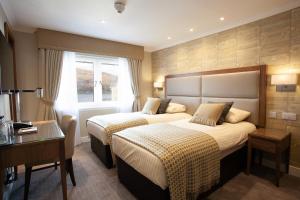 a hotel room with two beds and a desk at Cruachan Hotel in Fort William