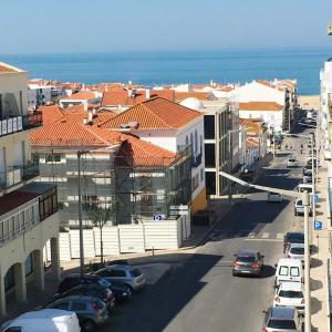 a city with cars parked on a street with buildings at Aloha Nazaré in Nazaré