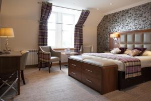 a hotel room with a bed, chair, table and lamps at Cruachan Hotel in Fort William