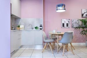 una cucina con tavolo, sedie e pareti rosa di Residence Leopoldo a Firenze