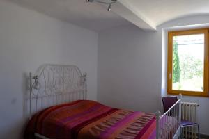 Una habitación blanca con una cama y una ventana en Chez la Nonna, en Saint-Jean-le-Centenier