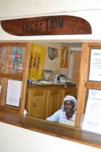 a woman sitting in front of a counter with a surfboard at Hotel Club Safari in Mbour