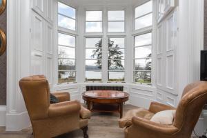 a room with two chairs and a table and windows at The Lake House, Wansfell Holme, Windermere in Ambleside