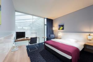ベルリンにあるSeminaris CampusHotel Berlinのベッドとデスクが備わるホテルルームです。