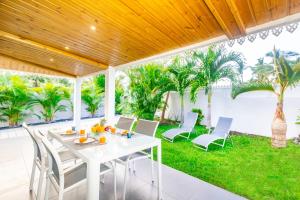una mesa blanca y sillas en un patio con palmeras en Lagoon ! Jolie villa à 2 pas du lagon de la Saline en La Saline les Bains