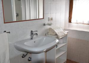 a white bathroom with a sink and a mirror at Casa Vacanze Porta Vecchia in Montalcino