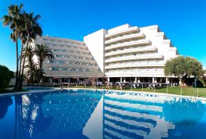 a hotel with a swimming pool in front of a building at Melia Sitges in Sitges
