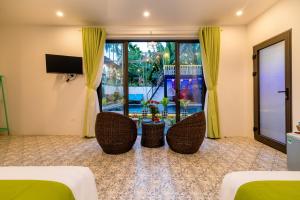 a room with two beds and two chairs and a television at Sunny Island Homestay in Hoi An