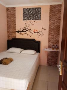 una camera da letto con un letto con un albero sul muro di nDalem Eyang Dwijo a Yogyakarta