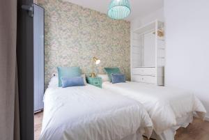 Duas camas brancas num quarto com papel de parede floral em Armenta Deluxe Suite by Valcambre em Sevilha