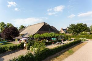 a barn with people sitting around tables in a garden at Vakantie Appartementen De Bonte Kraai in Raamsdonk