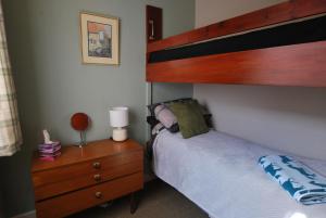 a bedroom with a bunk bed and a wooden dresser at 11 Laigh Isle in Isle of Whithorn