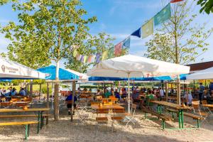 people sitting at tables and umbrellas at a restaurant at Camping & Pension Au an der Donau in Au an der Donau