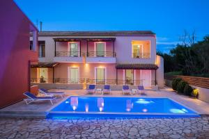 a villa with a swimming pool in front of a house at michael apartments in Corfu Town