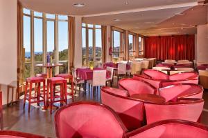 un restaurante con sillas rojas, mesas y ventanas en MLL Blue Bay, en Palma de Mallorca