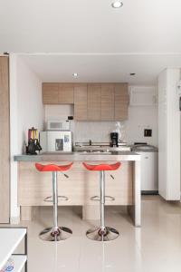 a kitchen with two red bar stools in front of a counter at Apartamento Poblado Frontera in Medellín
