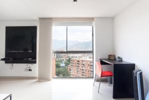 a living room with a desk and a large window at Apartamento Poblado Frontera in Medellín