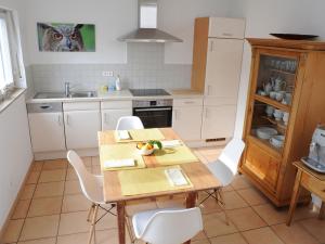 eine Küche mit einem Holztisch und weißen Stühlen in der Unterkunft Ferienhaus Sunny in Gengenbach
