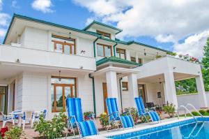 a house with a swimming pool and blue chairs at Villa Ramonte in Cetinje